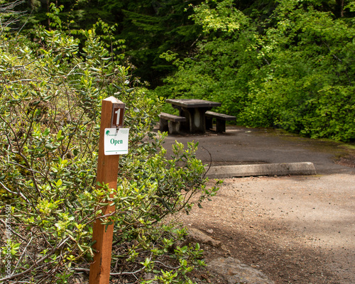 Oregon campground showing an open sign on a post at a vacant campsite indicating it can be reserved.