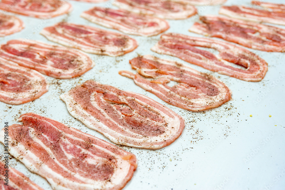 Thinly sliced bacon with garlic and spices are on the table. Cooking junk and fatty foods. Thinly sliced bacon with garlic and spices are on the table. Cooking junk and fatty foods.