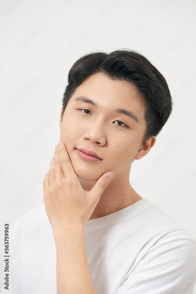 A handsome young man checking the skin on his face and smiling A handsome young man checking the skin on his face and smiling