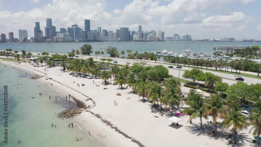 Aerial view of beautiful white sand beach at the picturesque highway on a sunny day. 4K drone shot of cars driving with amazing bay view in the direction of Miami downtown, Florida, USA. Aerial view of beautiful white sand beach at the picturesque highway on a sunny day. 4K drone shot of cars driving with amazing bay view in the direction of Miami downtown, Florida, USA.