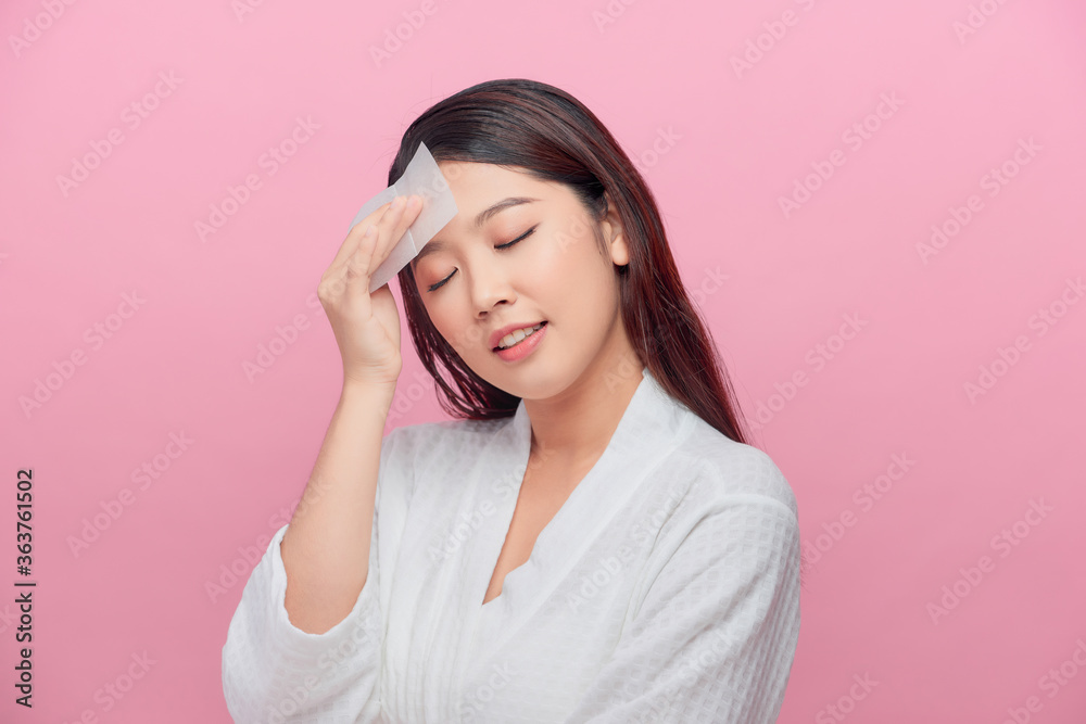 Young asian skin care woman smile and use oil blotting paper on her face Young asian skin care woman smile and use oil blotting paper on her face