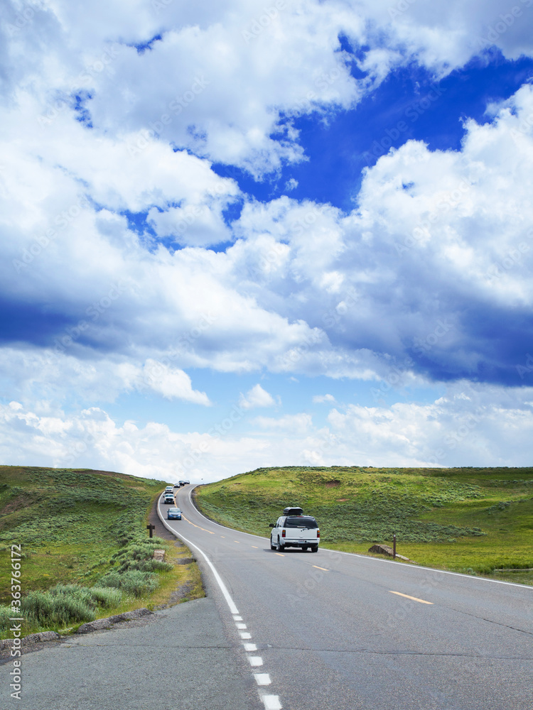 Straight road with cars under cloudy sky