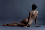 Full Length Of Naked Woman Sitting Against Gray Background
