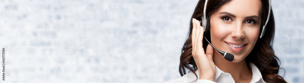 Face portrait of support phone operator in headset, against white brick wall background. Consulting and assistance service call center. Face portrait of support phone operator in headset, against white brick wall background. Consulting and assistance service call center.