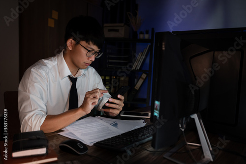 Asian businessman concentrated working until late overtime in office at night 