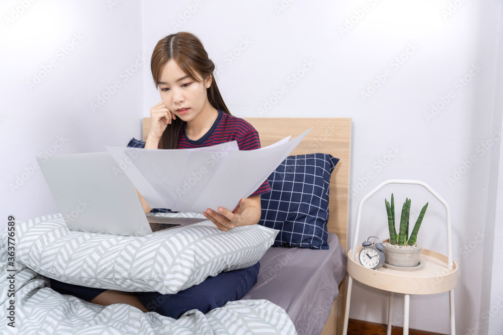 Asian woman working with smartphone or laptop in bedroom at her home
Asian woman working with smartphone or laptop in bedroom at her home