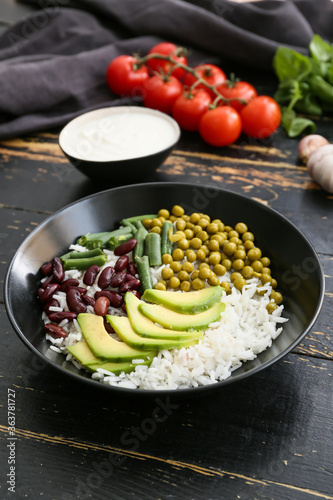Bowl with tasty rice, beans and avocado on table