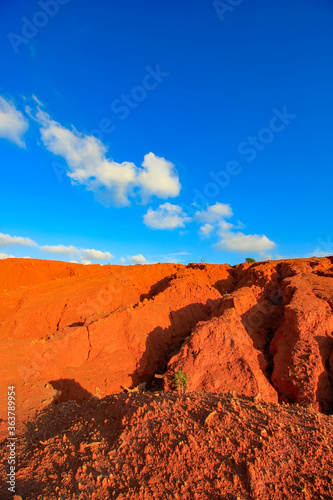 The red land is under the blue sky and white clouds.