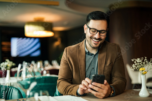 Cheerful man using smart phone in the restaurant, close-up, portrait. © bnenin