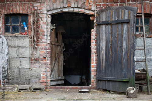 Wejście do gospodarczego pomieszczenia z drewnianymi drzwiami, w starym wiejskim budynku.