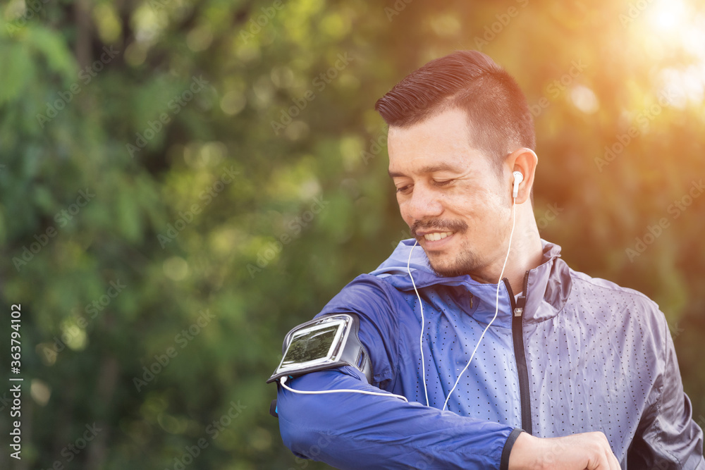 Obraz premium A man in sport hoodie jogging in the city park in the evening after stressful work. Runner jogging training and workout exercising power walking outdoors in forest city. Stock photo