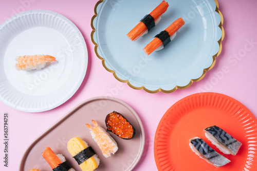 Top view - Japanese sushi variety set on plates over pink background. photo