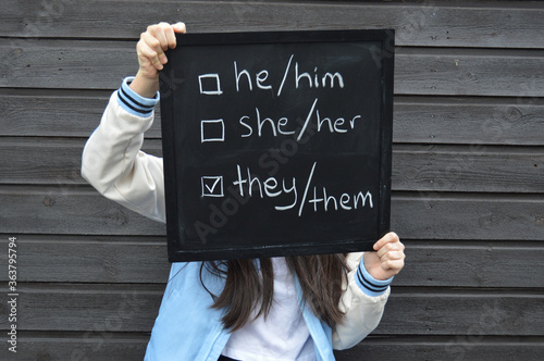 Teenager with a black board showing selection for gender identity pronouns - male, female and non-binary options photo