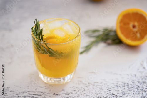 Refreshment drink with orange  and rosemary herb on white concrete background. Summertime beverage for hot days.