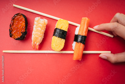Top view - Sushit set salmon shrimp egg roll crab stick with chopstick over red background.