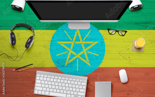 Ethiopia flag background with headphone,computer keyboard and mouse on national office desk table.Top view with copy space.Flat Lay.