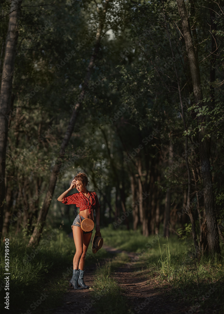 girl in a red top and shorts walks through the woods
