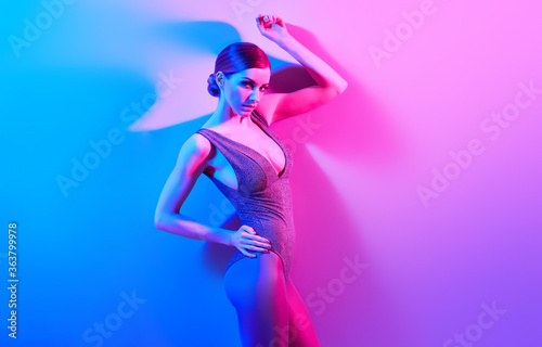 High Fashion. Woman in colorful neon light, make-up. Sexy girl, stylish hair, trendy bodysuit, makeup. Party disco neon style. Creative art beauty concept, fashionable fitness model, bright color