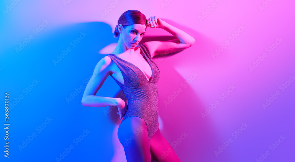 High Fashion. Woman in colorful neon light, make-up. Sexy girl, stylish hair, trendy bodysuit, makeup. Party disco neon style. Creative art beauty concept, fashionable fitness model, bright color