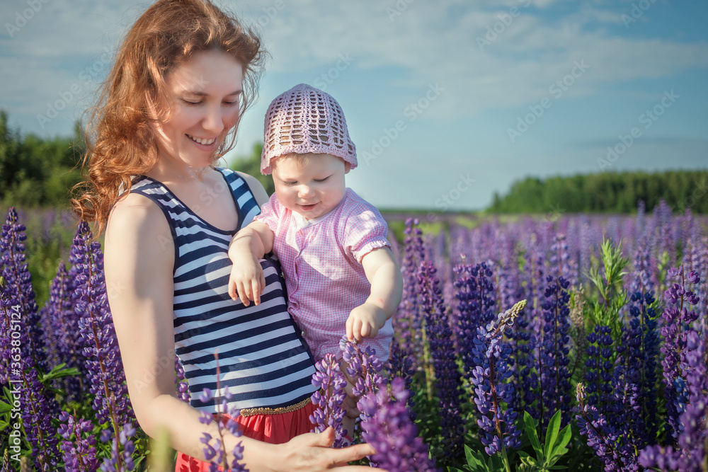 Mother and child laughing and playing in the summer at the lilac and violet lupinus field. Mother and child laughing and playing in the summer at the lilac and violet lupinus field.
