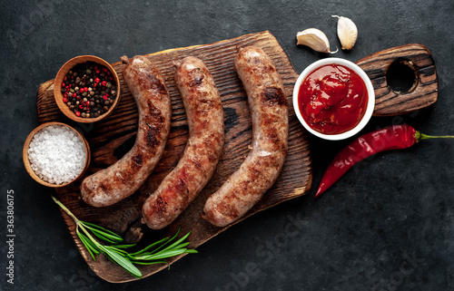 grilled sausages with spices and rosemary on a stone background