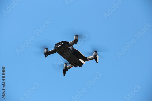 Flying drone with blue sky background controlled by professional photographer