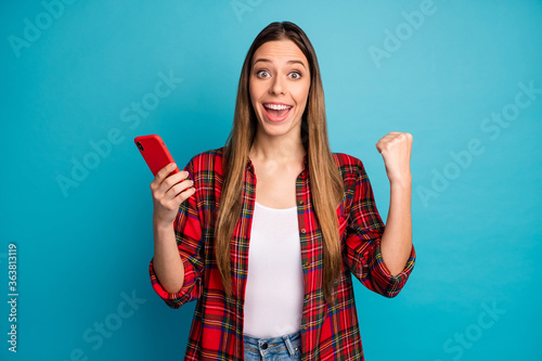 Portrait of her she nice attractive pretty lovely cheerful cheery long-haired girl wearing checked shirt using cell having fun isolated over bright vivid shine vibrant blue color background