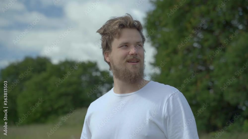 A young attractive male on the field background looks funny and then serious A young attractive male on the field background looks funny and then serious