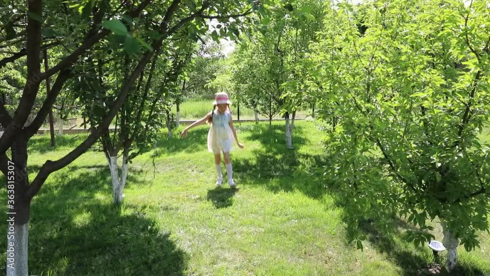 Trees around. Space for text. little beautiful girl in a dress runs through the garden, park. Trees around. Space for text. little beautiful girl in a dress runs through the garden, park.