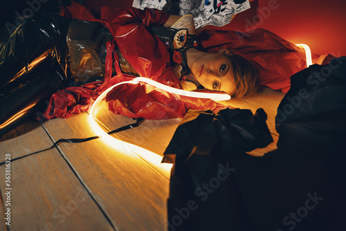Woman in red vinyl coat and red glossy gloves with neon light