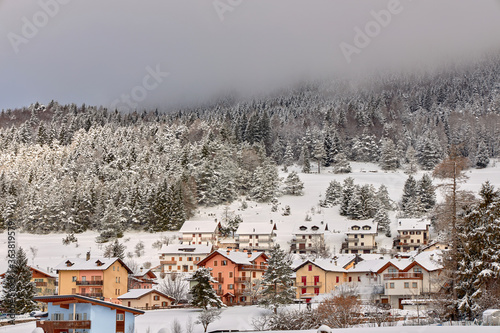 View of a small beautiful village in winter. Against background of dense forest