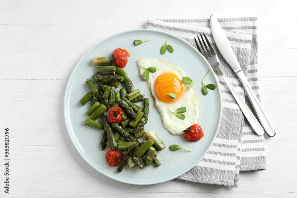 Oven baked asparagus served with fried egg on white wooden table, flat lay Oven baked asparagus served with fried egg on white wooden table, flat lay