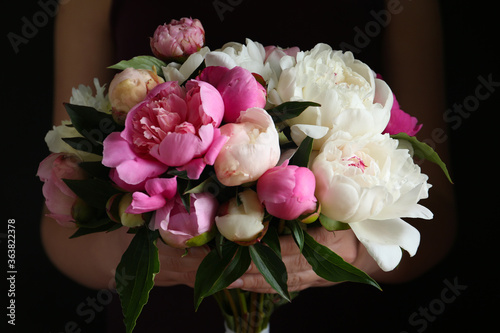 Fototapeta Naklejka Na Ścianę i Meble -  Woman with bouquet of beautiful peonies on black background, closeup