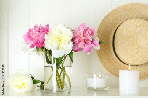 Fototapeta Naklejka Na Ścianę i Meble -  Bouquet of beautiful peonies in vase and candles on white table