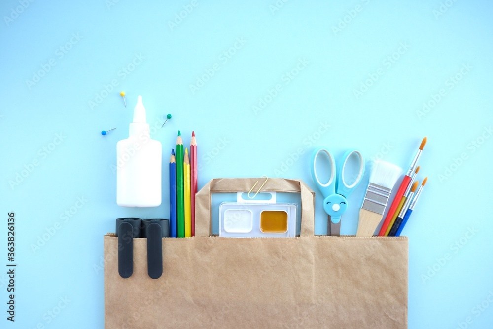 Different stationery for creativity (Scissors, markers, paints, brushes, pencils, colored paper) on blue background.Stationery delivery.Getting ready for school. Different stationery for creativity (Scissors, markers, paints, brushes, pencils, colored paper) on blue background.Stationery delivery.Getting ready for school.
