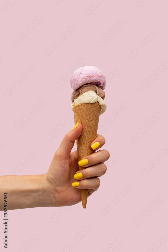 Woman's hand holding an ice cream over a pink background Woman's hand holding an ice cream over a pink background