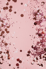 Pink celebration background with holiday sparkling confetti. Flat lay, top view