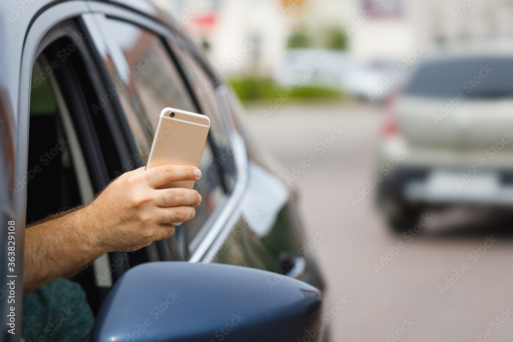 Man uses mobile phone from a car window. Background is blurred. Copy space. Man uses mobile phone from a car window. Background is blurred. Copy space.