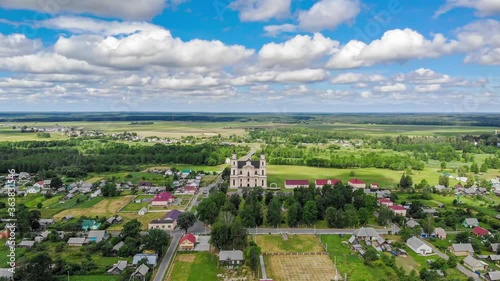 Flying over Budslav - village with Catholic church in Belarus and undeк the clouds. Drone aerial timelapse 4K video photo