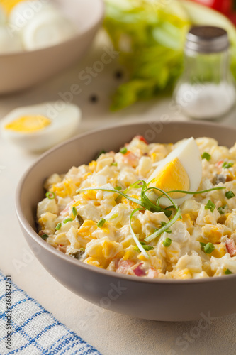 A light egg salad with celery, gherkin, pepper and mayonnaise. Served in a bowl on a light background. Front view.