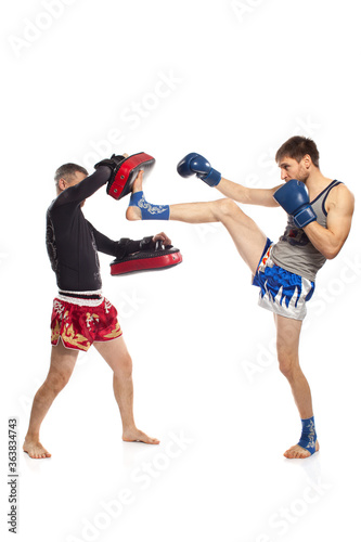 Two caucasian men exercising thai boxing in studio on white background