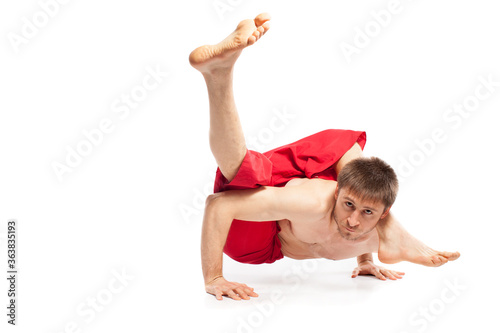 Caucasian adult man doing yoga exercises in studio at white background 