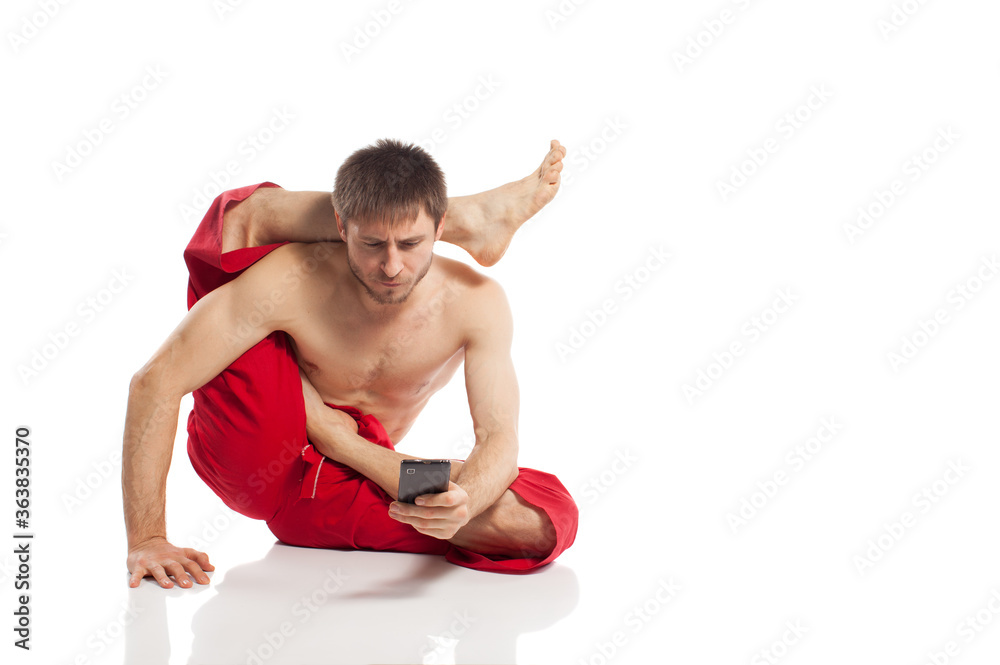 man doing yoga exercises and use mobile phone for message at white background 