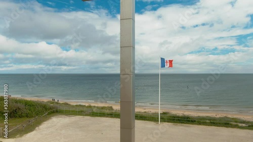 Cross memorial on Juno beach, Normandy flag in remembrance of heroes fallen during WWII fights 