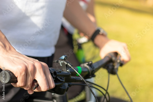 Close up of a mans hand holding onto the bicycle steering wheel  holding the brake pressed. Both hands seen  prepairing to start cycling outdoors