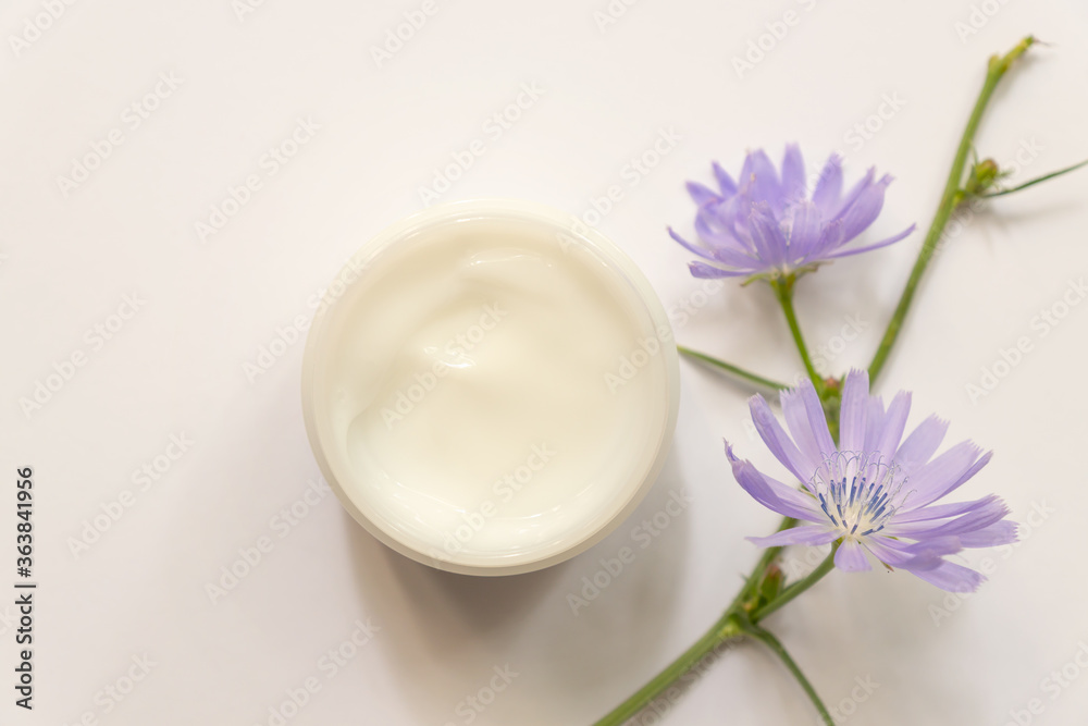 Moisturizing cream jar and chicory top view . Natural cosmetology product, organic cosmetics creative concept. white plastic container with facial, body balm. Women skin care.