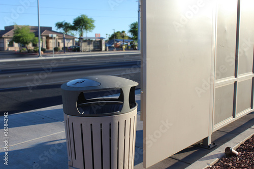 Photo trash bin outside by thew bus stop and  street