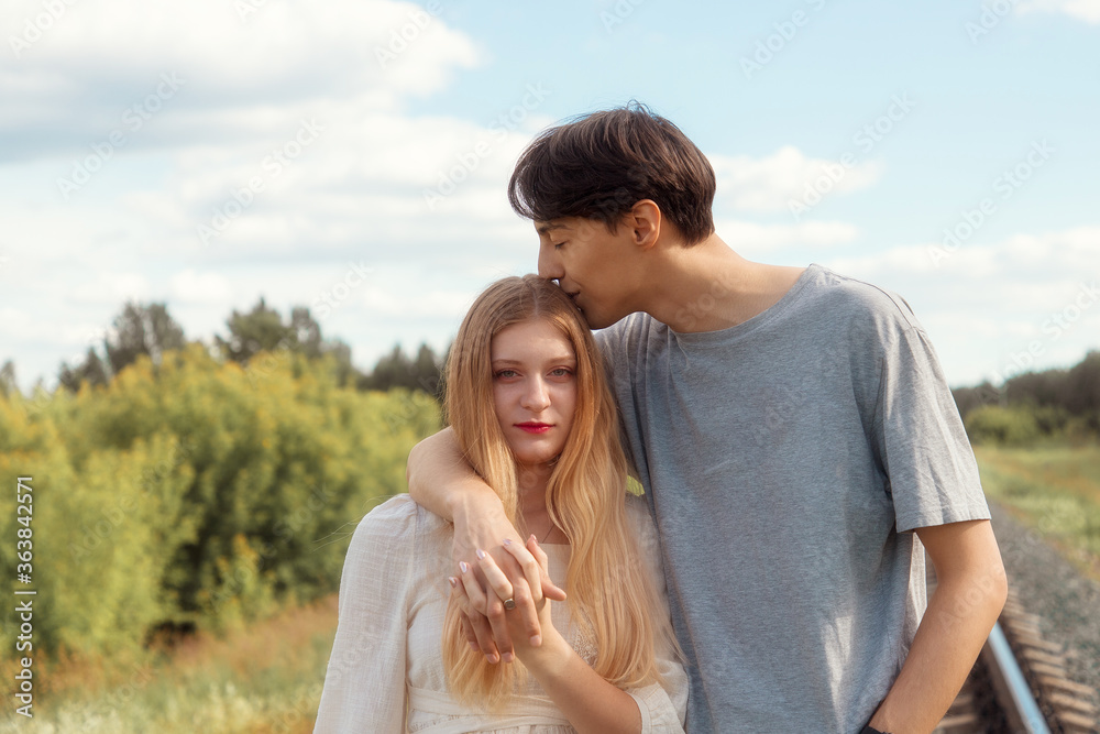 Blonde girl and dark hair guy happily together in nature, love story