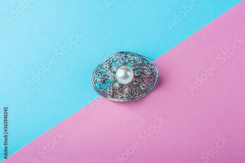 Foto Vintage pearl jewelry brooch on pink blue background
