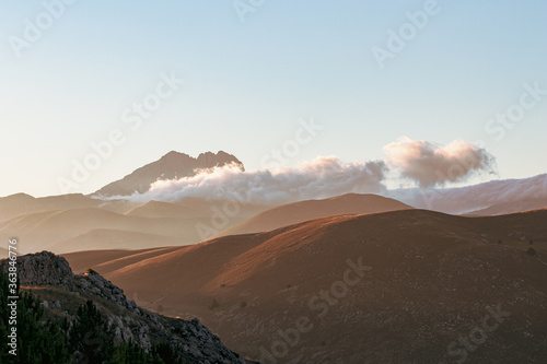 Mountain landscape at sunset with foggy clouds and golden light. Peaceful background and relax landscape. Banner and wallpaper images, backdrop and background with mountain peaceful light